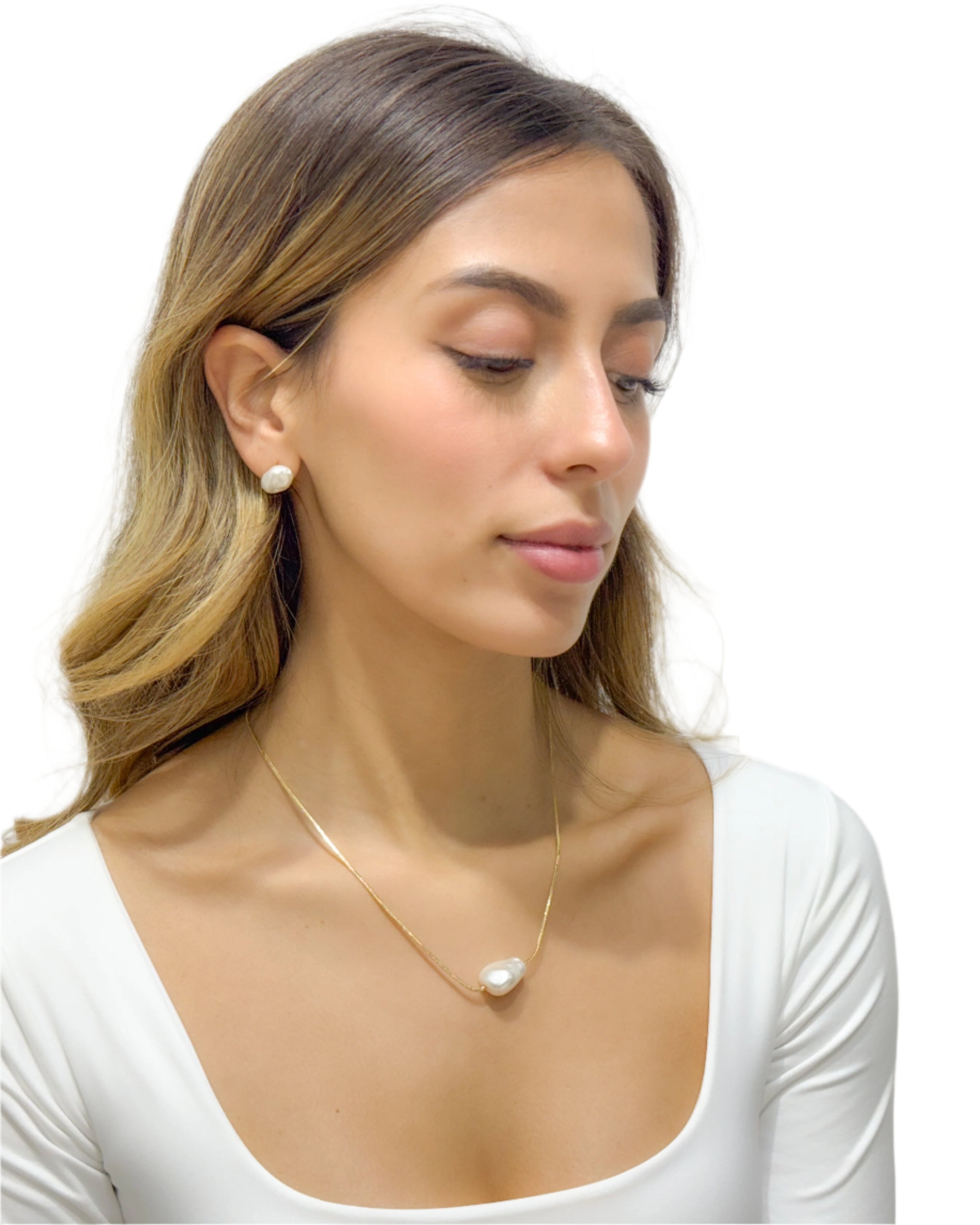 Woman wearing a gold necklace and earrings against a plain background